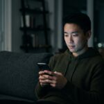 Person alone at night lit by phone screen glow representing AI entertainment and the loneliness epidemic